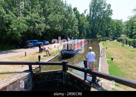 Ein schmales Boot, das an einem heißen Sommertag in Surrey England durch die Pyrford-Schleuse auf dem River Wey Navigationskanal fährt Stockfoto