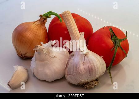 Stillleben von Knoblauch, Zwiebeln und Reben, gereifte Tomaten auf der Küchentheke, 2023, USA Stockfoto