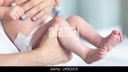 Neugeborenes in den Händen der Mutter, Beine im Nahbereich. Stockfoto