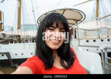 Selfie-Foto einer jungen lateinischen Frau venezolanischer ethnischer Herkunft, lächelnd auf einer Bootsfahrt, Porträt mit Telefonperspektive, Menschen und Technologie Stockfoto