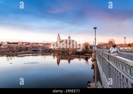 Salamanca, Spanien - 20. Februar 2022: Blick auf die Skyline von Salamanca mit Kathedrale und Enrique-Estevan-Brücke am Tormes River bei herrlichem Sonnenuntergang. Stockfoto