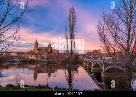 Salamanca, Spanien - 20. Februar 2022: Blick auf die Skyline von Salamanca mit Kathedrale und Enrique-Estevan-Brücke am Tormes River bei herrlichem Sonnenuntergang. Stockfoto