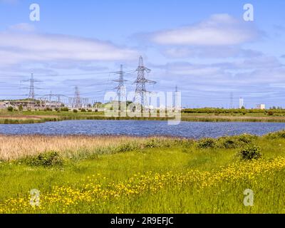 Pylonen an der National Grid Salthome Umspannstation mit Naturschutzgebiet und See im Vordergrund Stockfoto