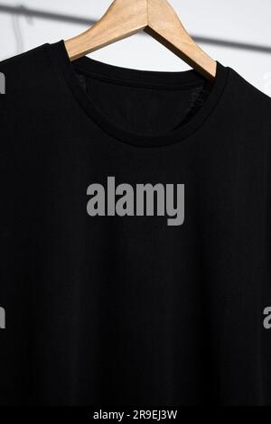 Schwarzes T-Shirt-Modell, Schablone auf Holzbügel Stockfoto