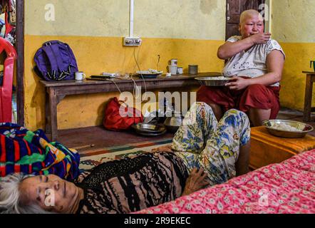 Krebspatientin Chinkhothang Baite (47) isst zu Mittag, während ihre kranke Mutter in einem Hilfslager im Dorf Rengkia auf einem Bett liegt. Am 3. Mai 2023 brach im nordöstlichen indischen Bundesstaat Manipur ein ethnischer Konflikt zwischen dem Volk der Meitei, das mehrheitlich im Imphal-Tal lebt, und den Stammesgemeinschaften in den umliegenden Bergen, einschließlich Kuki und Zo, aus. Mindestens 109 Menschen sind bei ethnisch motivierter Gewalt zwischen der Meitei und den Kuki im indischen Bundesstaat Manipur ums Leben gekommen und über 300 wurden verletzt. (Foto: Biplov Bhuyan/SOPA Images/Sipa USA) Stockfoto