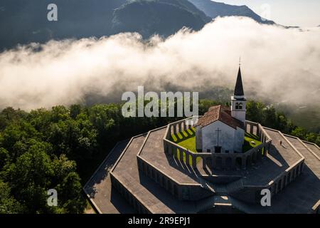 Drohnenblick auf die St.-Anton-Kirche und das Kobarid-Ossarium in Slowenien. Caporetto Memorial aus dem Ersten Weltkrieg. Stockfoto