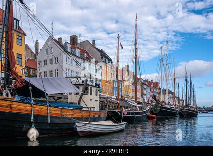 Kopenhagen, Dänemark - 14. September 2010: Langer Abschnitt der farbigen Fassaden der Nyhavn-Restaurantreihe und kleine Segelboote auf dem Wasser unter blauer Wolkenlandschaft Stockfoto