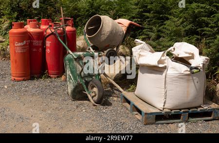 Herm, Kanalinseln. 11. Juni 2023 Bauernhof auf der Insel Herm Butane mit Gasflaschen, Zementmischer, Schubkarre und einem Trümmersack. Stockfoto