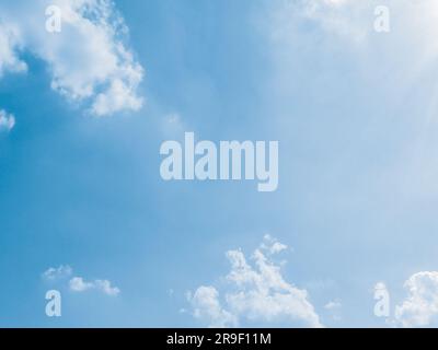 Sommerhimmel mit flauschigen Wolken im Hintergrund. Die Sonne strahlt ihre Brillanz aus und umhüllt die Szene in einem warmen Licht. Driftende Wolken geben einen Eindruck von Stockfoto