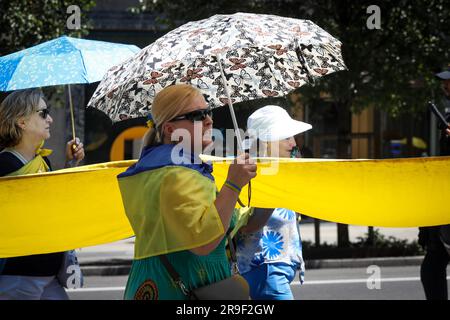 Madrid, Spanien. 25. Juni 2023. Eine Frau mit einer ukrainischen Flagge schützt sich während einer Demonstration mit einem Schirm vor der Sonne. Wie jeden Sonntag und trotz der hohen Temperaturen in Spanien kommen die ukrainischen Bewohner in Madrid am 25. Juni heraus, um im Zentrum der Stadt zu demonstrieren und ein Ende der russischen Invasion ihres Landes zu fordern. Kredit: SOPA Images Limited/Alamy Live News Stockfoto