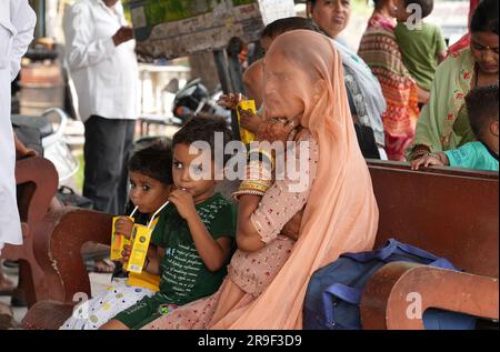 Beawar, Indien, 25. Juni 2023: Rajasthani Frau mit ihren Kindern wartet an einem heißen Sommertag in Beawar auf den Bus an der Bushaltestelle auf der Straße. Kredit: Sumit Saraswat/Alamy Live News Stockfoto