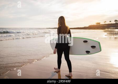 Solo-Surfer. Junge Frau In Neoprenanzug Mit Surfbrett Auf Dem Weg Nach Ocean Stockfoto