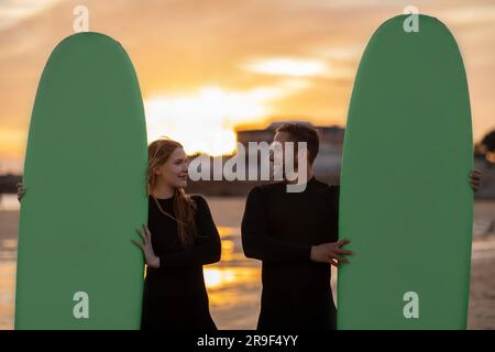 Porträt Von Happy Surfer-Paar, Das Mit Ihren Surfbrettern Am Strand Posiert Stockfoto