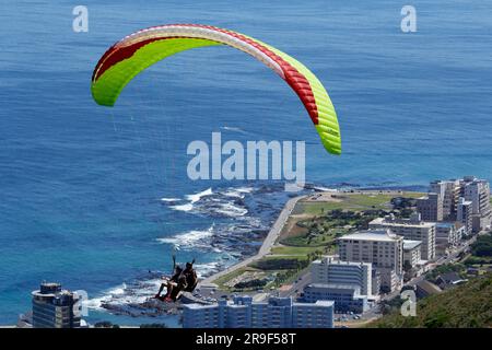 Gleitschirmfliegen vor der Vorderseite des Tafelbergs oder mit einem Stadtrand als Kulisse. Stockfoto