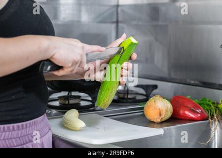 Detaillierte Ansicht der Hände eines lateinischen Mädchens, die die Schale einer grünen Banane entfernen, um sie zu hacken und Patacone zu machen Stockfoto