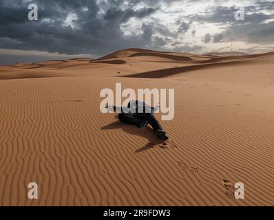 Eine Person, die vorgibt, tot in der Erg Chebbi Wüste in Marokko zu liegen Stockfoto