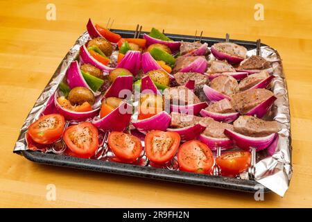 Rind- und Gemüsekabben bereit zum Grillen im Sommer. Buntes Tablett mit Shish Kabobs auf Holztisch. Stockfoto