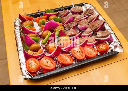 Rind- und Gemüsekabben bereit zum Grillen im Sommer. Buntes Tablett mit Shish Kabobs auf Holztisch. Stockfoto