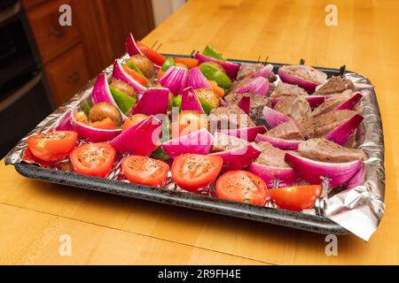 Rind- und Gemüsekabben bereit zum Grillen im Sommer. Buntes Tablett mit Shish Kabobs auf Holztisch. Stockfoto