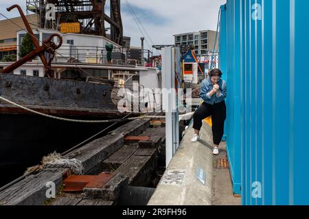 Eine junge Frau nimmt eine heimliche Zigarette hinter einem Container in der Hafengegend von Wellington, New Zealand Capital City. Foto: Rob Watkins Stockfoto