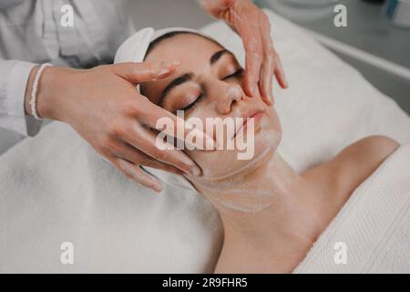 Frau, die Creme auf das Gesicht des Kunden aufträgt Stockfoto