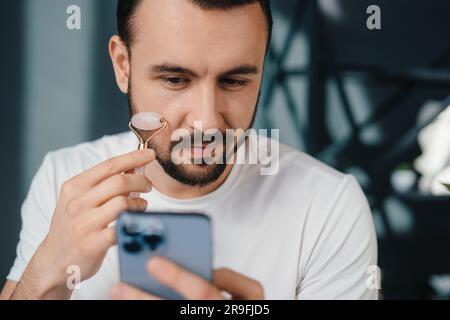 Junger Mann mit einer Tasse Kaffee über Smartphone Stockfoto