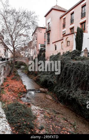 Granada, Spanien – 26. Februar 2022: Steinbrücke und traditionelle maurische spanische Architektur rund um den Fluss Darro, Granada, Spanien. Stockfoto