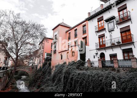 Granada, Spanien – 26. Februar 2022: Steinbrücke und traditionelle maurische spanische Architektur rund um den Fluss Darro, Granada, Spanien. Stockfoto