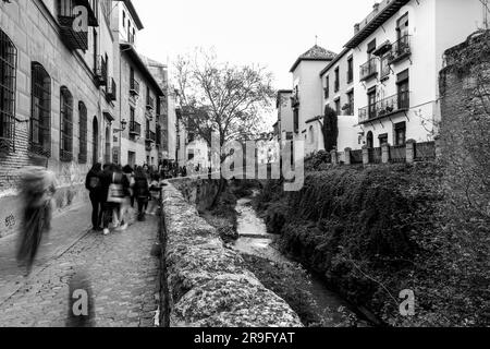 Granada, Spanien – 26. Februar 2022: Steinbrücke und traditionelle maurische spanische Architektur rund um den Fluss Darro, Granada, Spanien. Stockfoto