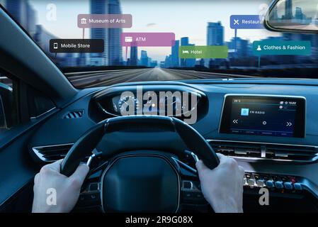 Blick aus der ersten Person auf die Fahrt entlang einer Stadtstraße. Augmented-Reality-Navigation mit Anzeige von Stadtstandorten für eine nahtlose und intuitive Erkundung Stockfoto