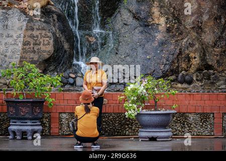 Ha Long, Vietnam - 19. März 2023. Eine vietnamesische Frau posiert für ein Foto vor einem Wasserfall. Stockfoto