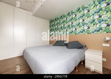 Doppelzimmer mit einem großen Bett mit Papierwänden und weißen Einbauschränken mit weißen Holztüren Stockfoto