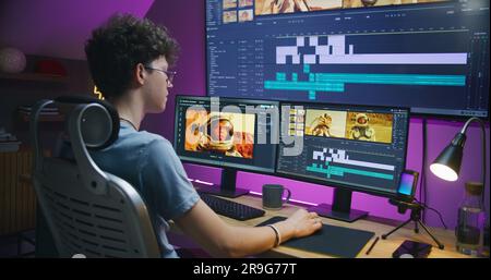 Junge Redakteurin, Videofilmer bearbeitet Filme mit Astronauten, arbeitet im Home Office. Filmmaterial und Programmschnittstelle mit Tools und Soundtracks auf Computer und großem digitalen Bildschirm. Postproduction-Konzept. Stockfoto