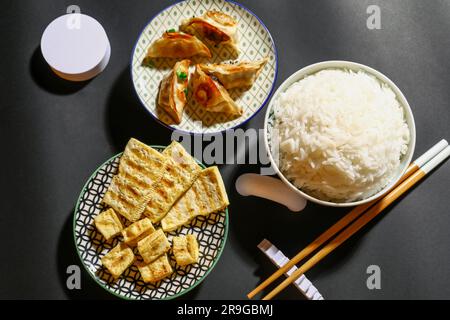Leckeres chinesisches Essen und Essstäbchen auf dunklem Hintergrund Stockfoto