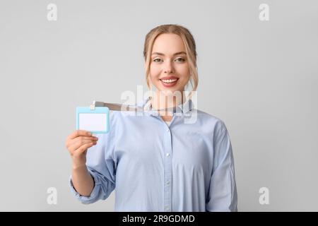 Junge Frau mit leerem Abzeichen auf grauem Hintergrund Stockfoto