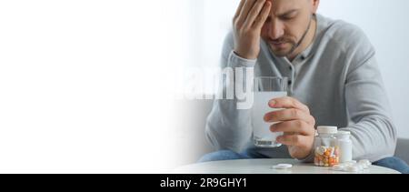 Ein Mann, der ein Glas Medizin für einen Kater zu Hause hält, Nahaufnahme. Banner mit Platz für Text Stockfoto