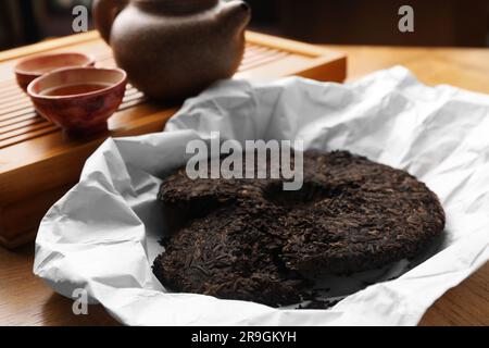 Gebrochener, scheibenförmiger pu-erh-Tee auf einem Holztisch Stockfoto