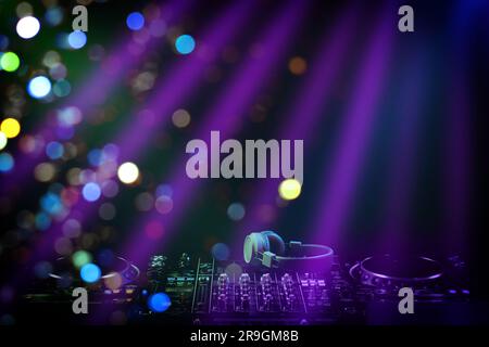 Moderner DJ-Controller und Kopfhörer unter Lichtstrahlen im Nachtclub, Bokeh-Effekt Stockfoto