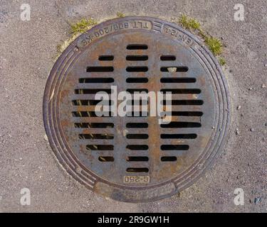 Runde Metallabdeckung für Regenablauf auf Asphalt, Draufsicht Nahaufnahme. Stockfoto