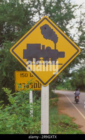 Ein Warnschild für Bahnübergänge neben der berüchtigten Todeseisenbahn aus dem Zweiten Weltkrieg in Thailand. Stockfoto