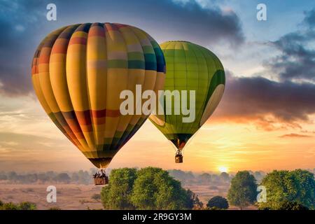 Zwei farbenfrohe Heißluftballons voller Touristen schweben bei Sonnenaufgang über der Landschaft, Teil der jährlichen Pushkar Camel Fair in Rajasthan, Indien. Stockfoto