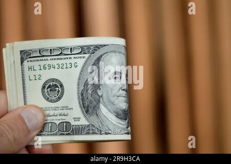 Ich habe 100 100-Dollar-Banknoten in Bargeld gefaltet, mit dem Portrait von Präsident Benjamin Franklin über Overse und Unabhängigkeit hal Stockfoto