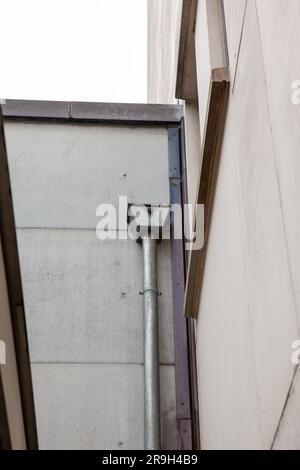 Auf einem großen Gebäude in der Stadt sehen Sie eine Regenwasserabflussleitung auf dem Zwischendach Stockfoto