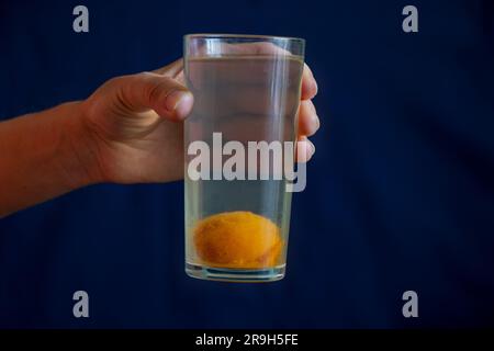 Ein Glas Kompott mit einer ganzen Aprikose unten in der Hand des Mädchens Stockfoto