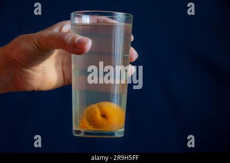 Ein Glas Kompott mit einer ganzen Aprikose unten in der Hand des Mädchens Stockfoto