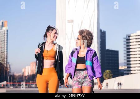 Zwei Frauen in Sportbekleidung, die sich beim Gehen unterhalten Stockfoto
