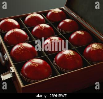 Eine Sammlung roter Cricketbälle mit goldenen Logos der zwölf mit dem ICC verbundenen Länder in einer mit Filz ausgekleideten Holzkiste – Juni Stockfoto