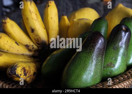 Ein Korb aus Korb mit frischen, reifen gelben Bananen und Avocados Stockfoto