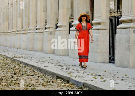 Spaziergang durch das Palais Royal in einem roten, bestickten Bauernkleid, eine glamouröse, reife asiatische Frau in Paris Stockfoto