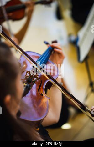 Detailansicht einer unkenntlichen Frau, die in der Öffentlichkeit Geige spielt. Stockfoto